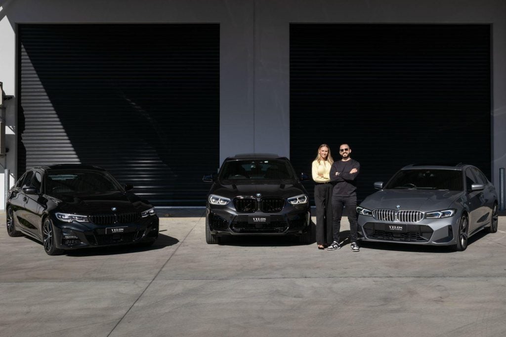 Turo host Lainey with her business partner, Ty, standing in front of their fleet of European cars available to rent on Turo.