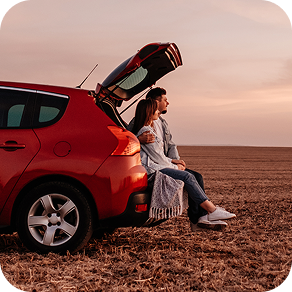 Couple sitting in back of a red car