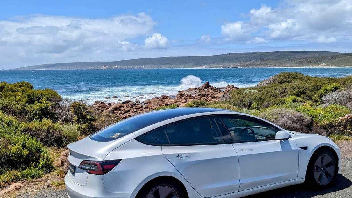A Tesla Model 3 by the ocean in Perth, the perfect car for a Perth to Albany road trip