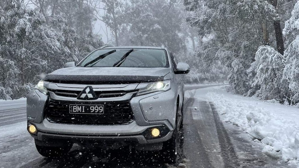 A Mitsubishi Pajero Sport on a snowy tree-lined road; ideal vehicle for a Melbourne to Canberra drive