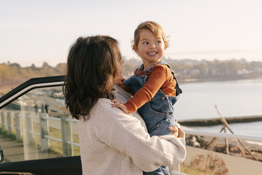  A mom and her child stand beside their vehicle while looking out over the water.