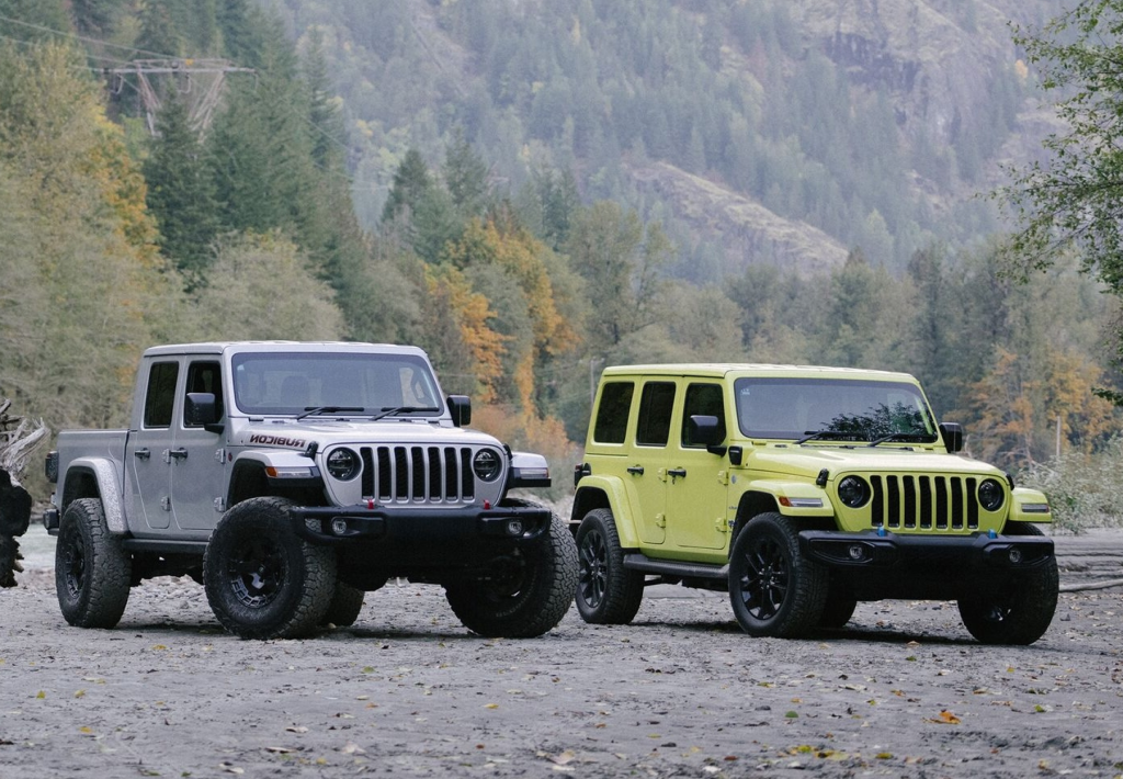 A pair of SUVs are parked near a tree-covered mountain.