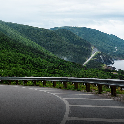 A coastal road winding through tree-covered hills.