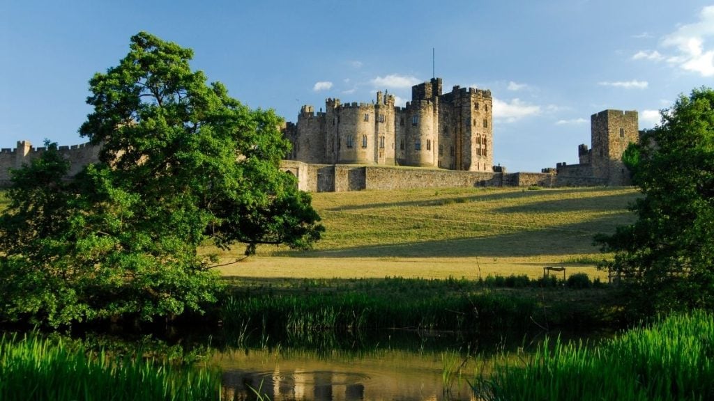 Alnwick Castle with stone towers and open lawns, located in the historic market town of Alnwick, Northumberland, England