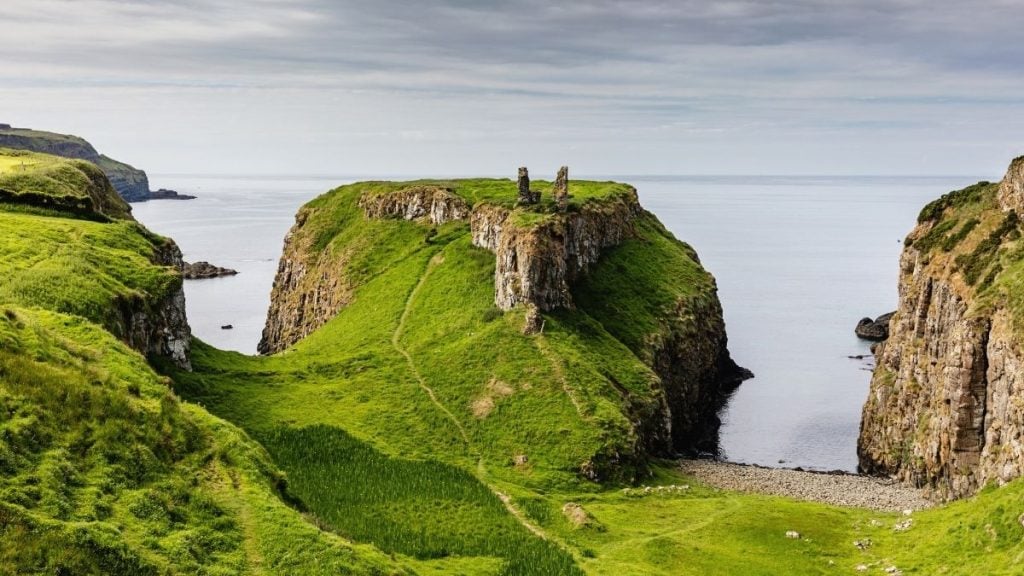 Ruins of Dunseverick Castle on a grassy clifftop overlooking the ocean, County Antrim, Northern Ireland