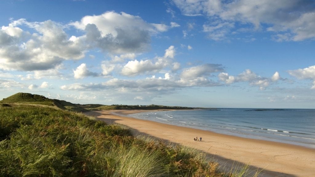 Embleton Bay shoreline with coastal footpath leading to Dunstanburgh Castle, Northumberland, England