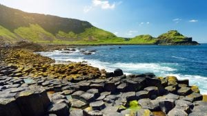 Giant’s Causeway rock formations along the Causeway Coastal Route in Northern Ireland, with hexagonal basalt columns and waves crashing in the background.