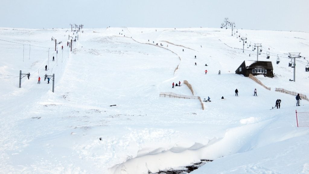 Skiers and ski lift at Glenshee Ski Centre with snow-covered slopes in the Cairngorms, Scottish Highlands, Scotland