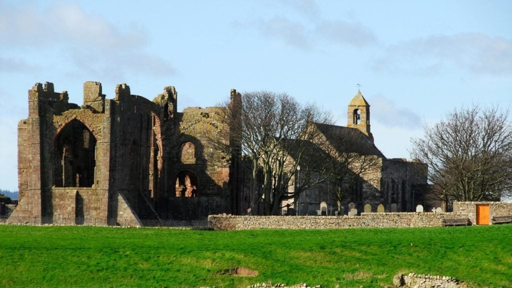 Ruins of Lindisfarne Priory on Holy Island with weathered stone arches and grassy grounds, Northumberland, England