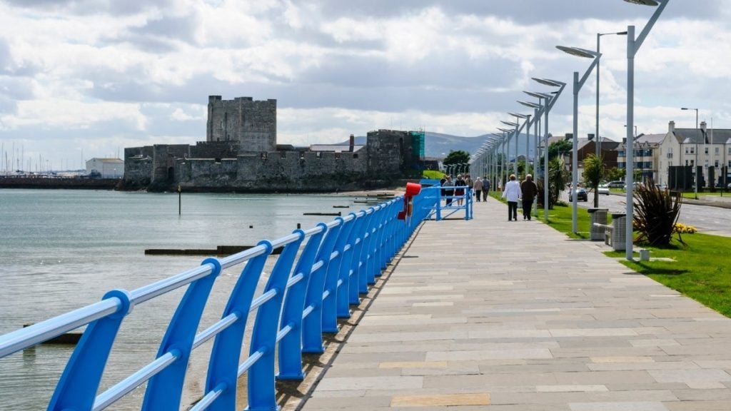Paved Carrickfergus Waterfront Walk along Belfast Lough with benches and marina views, County Antrim, Northern Ireland