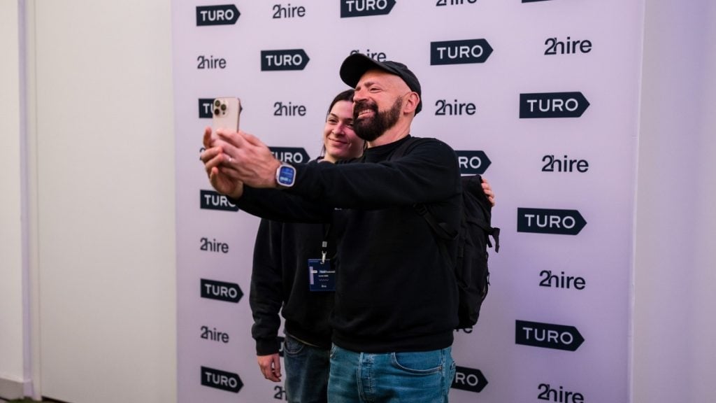 A Turo host taking a selfie with CEO Andre Haddad at the first UK Host Summit in London, following his keynote on the future of Turo, innovation, and host-driven growth.