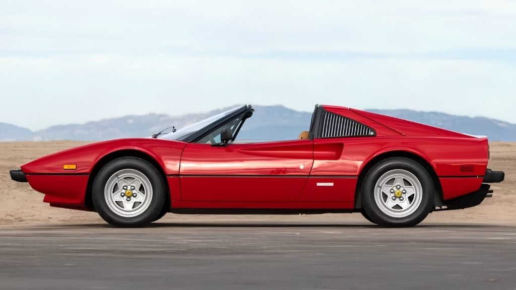Red 1982 Ferrari 308 GTS with removable targa roof off, side profile against mountain backdrop
