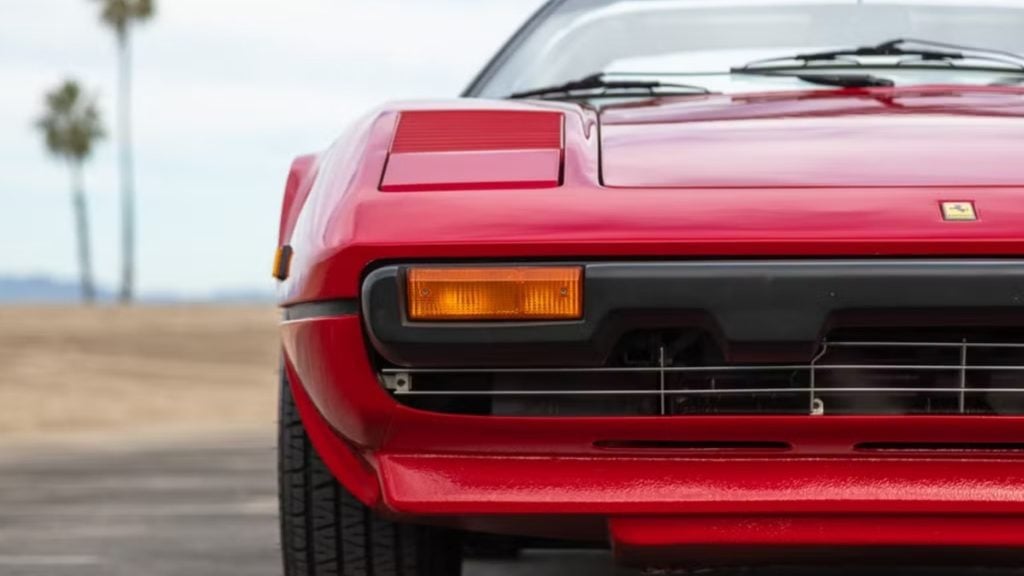 Close-up of a red 1982 Ferrari 308 GTS front end with pop-up headlights and Ferrari badge

