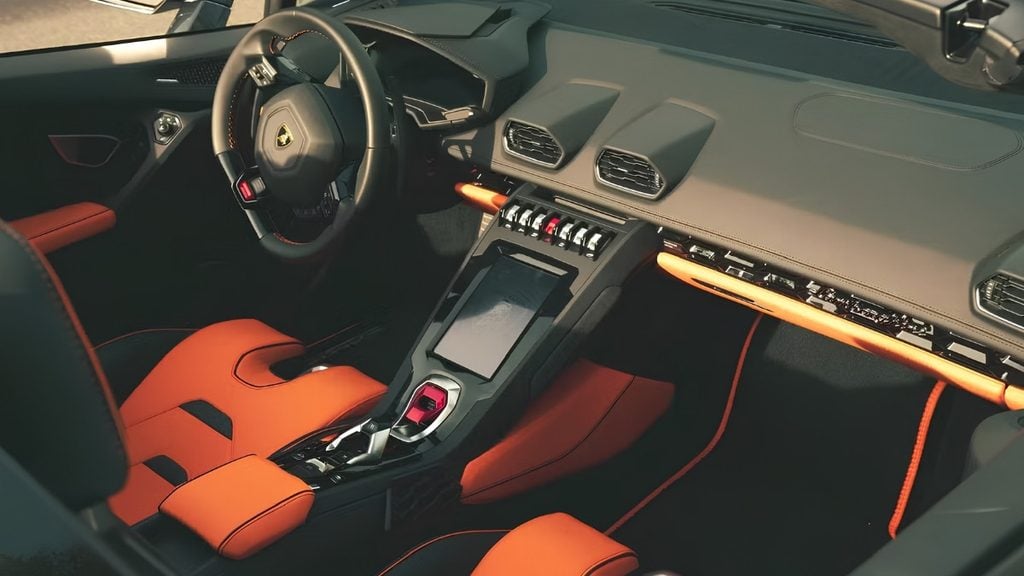 Lamborghini Huracán EVO interior with orange leather sport seats, centre touchscreen, metallic toggle switches and driver-focused cockpit.