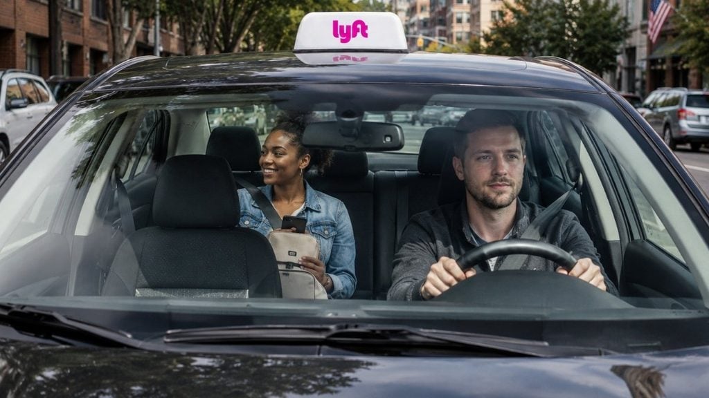 Young woman riding in a Lyft with a rideshare driver